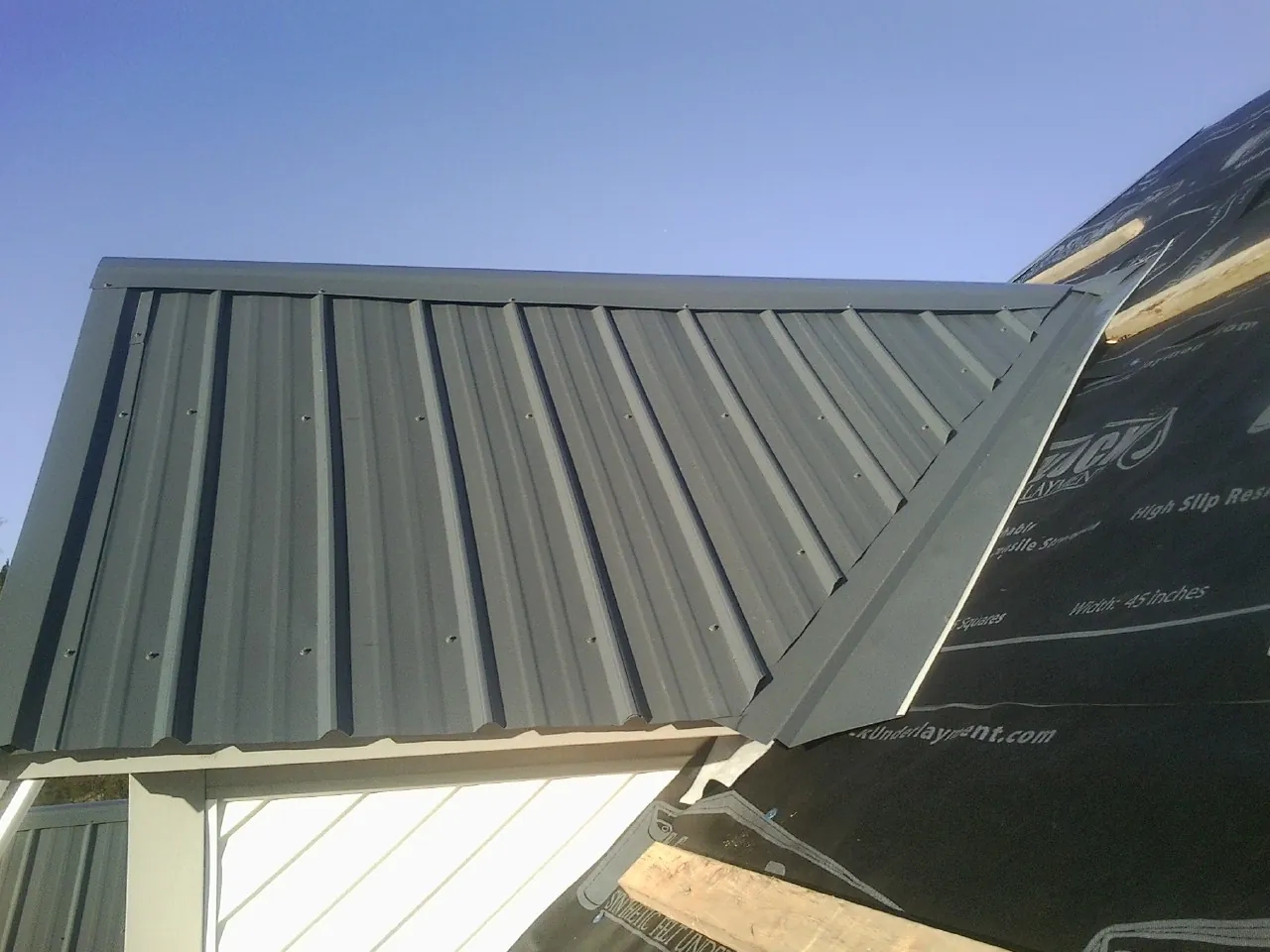 Gray metal roof panels going on over a garage gable in Whitewater