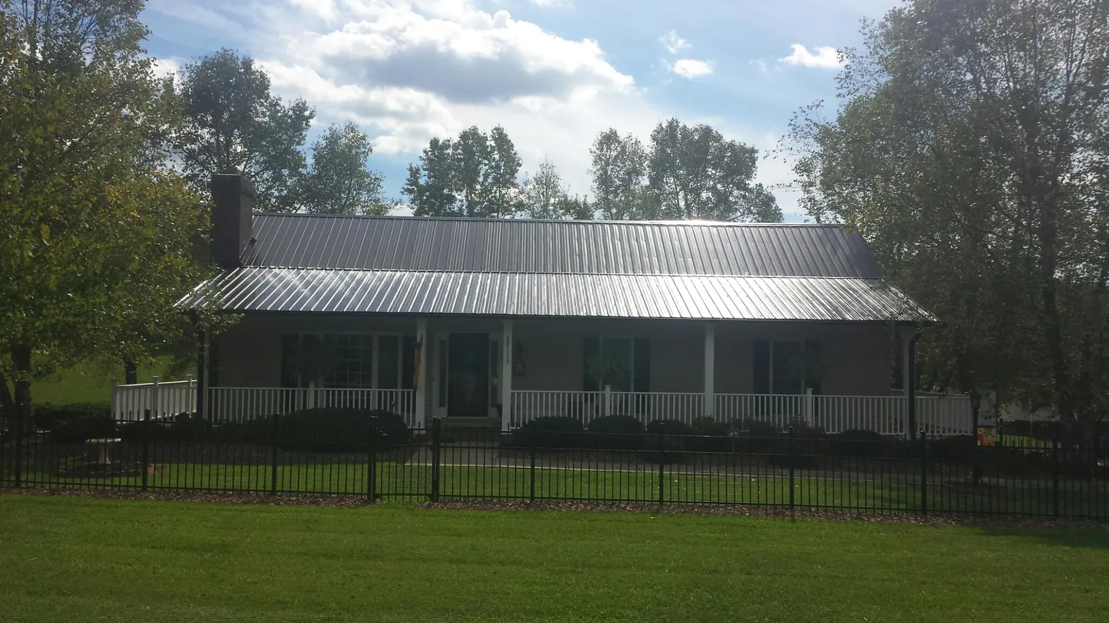 Gray metal roof on a brick ranch with a full width front porch — Gutter Guard Installation work by our crew in Whitewater
